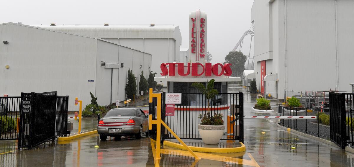 A vehicle is stopped next to an entry gate booth bearing a sign that reads Village Roadshow Studios 