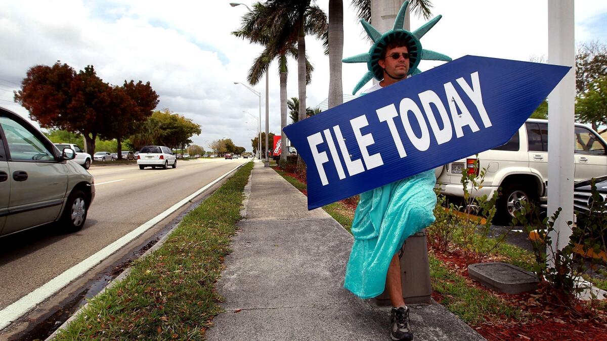 A man holds a sign advertising a tax preparation office in Miami, Fla. on April 14, 2010.