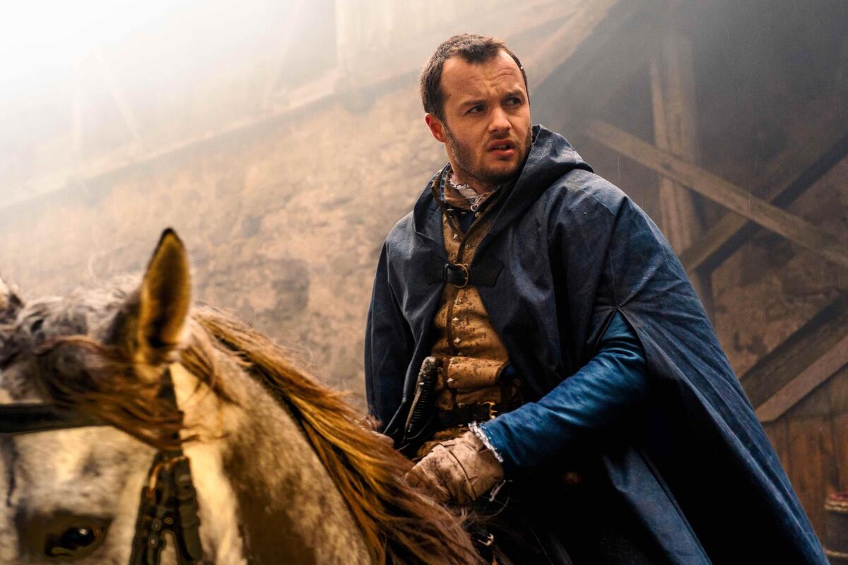 A man in a blue cape on horseback.