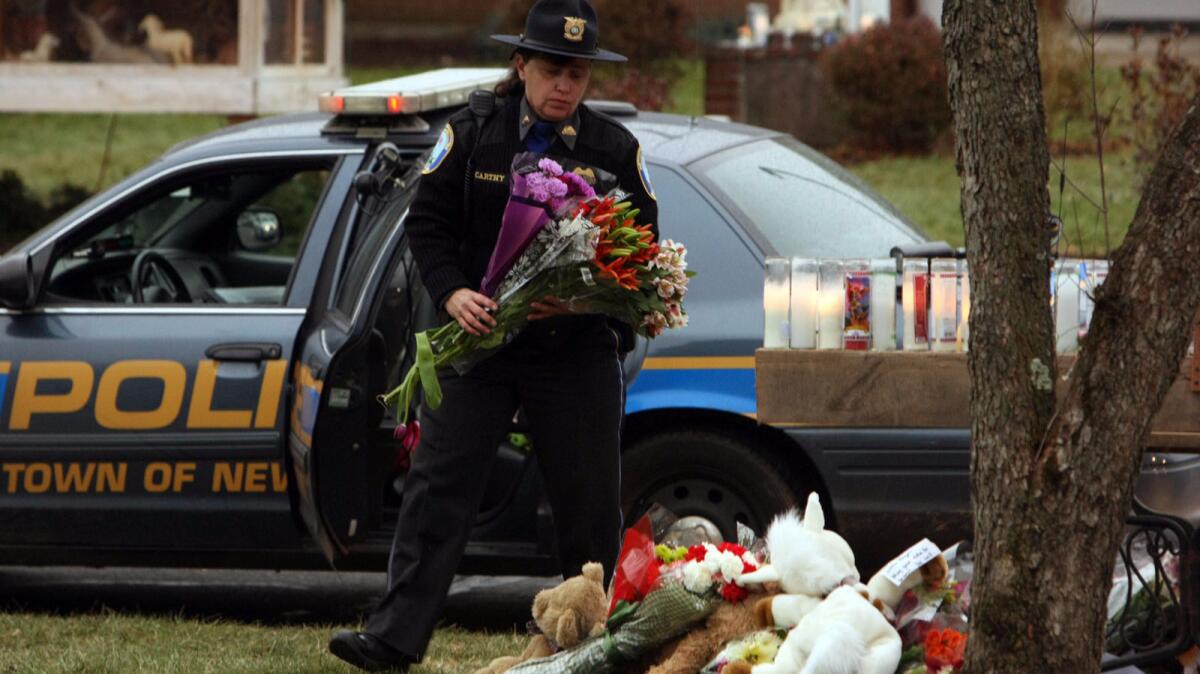 In 2012, a Newtown, Conn., police officer adds bouquets to a makeshift memorial at the St. Rose of Lima Church for victims of the Sandy Hook Elementary School shooting.