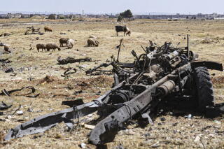A damaged vehicle sits amid the debris left by an Israeli strike on a military airbase near Ham
