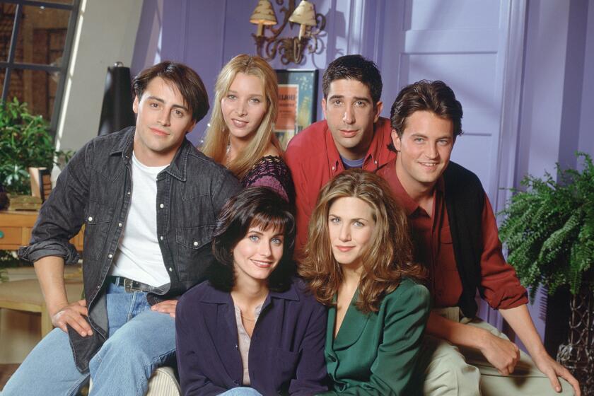 The cast of "Friends" sitting all together on a single couch and smiling