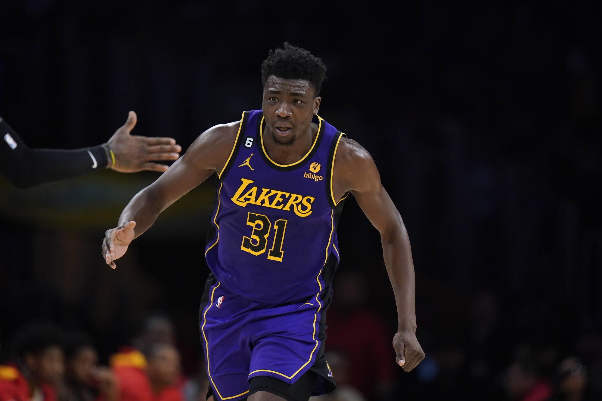 Lakers center Thomas Bryant makes his way back up the court as a teammate reaches from the sideline to slap hands.