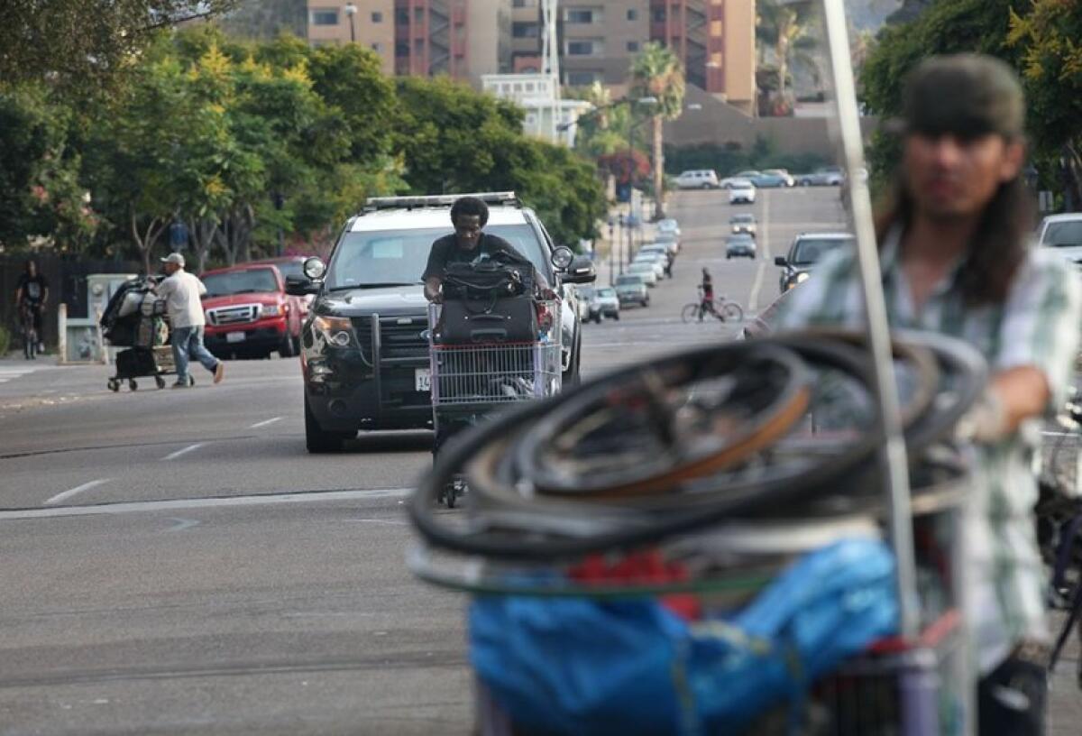 In a 2016 photo, a police car trails a homeless man during a clean-up alongside 17th Street.