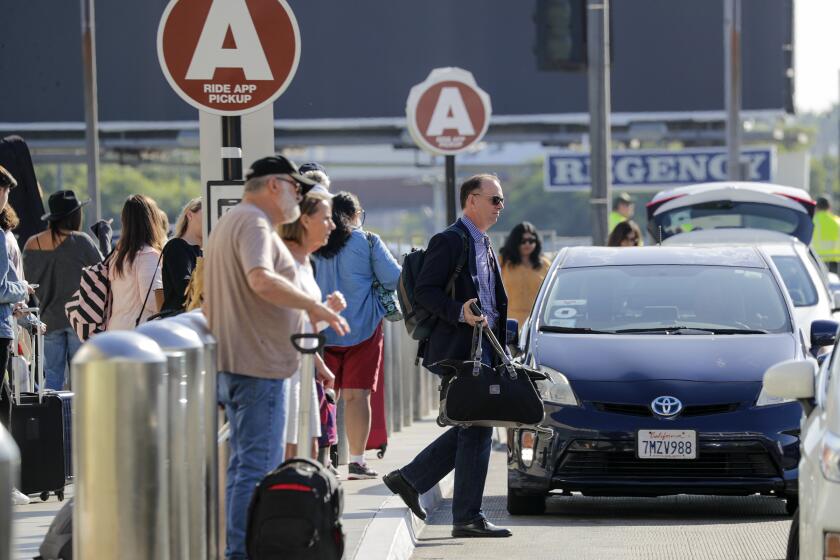 LOS ANGELES, CA - OCTOBER 04, 2019 — Present dedicated ride-hailing spot located at LAX departure level is crowded with passengers waiting for their ride. Los Angeles International Airport will soon ban ride-hailing companies from picking up passengers outside its terminals. Starting on or about Oct. 29, travelers looking to hop on an Uber or Lyft will be taken by shuttle to a parking lot next to Terminal 1, where they can book their rides. (Irfan Khan/Los Angeles Times)