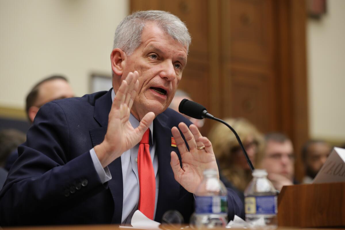Former Wells Fargo Chief Executive Timothy Sloan speaks into a microphone while holding up his hands in front of his chest