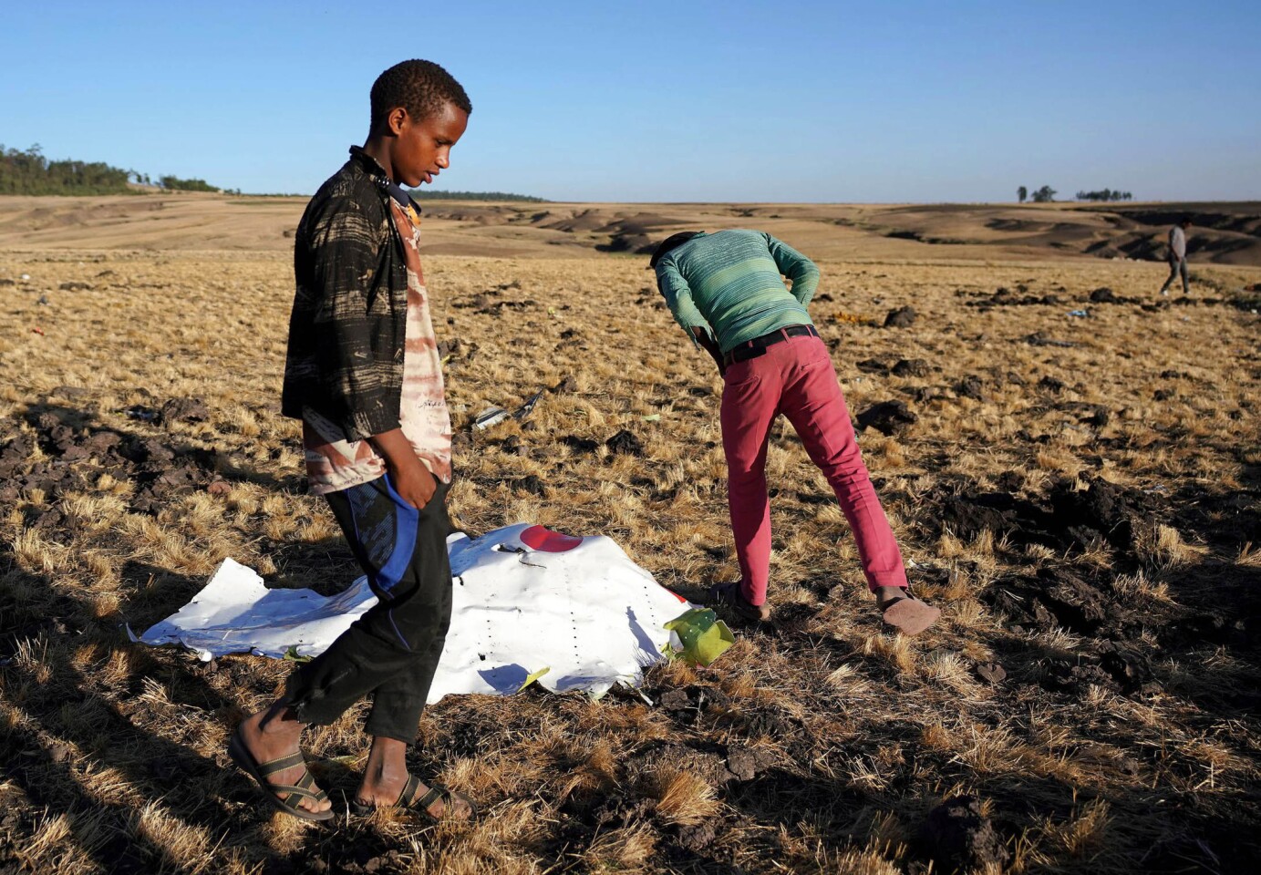 Local residents look at debris at the scene where Ethiopian Airlines Flight 302 crashed in a wheat field just outside the town of Bishoftu.