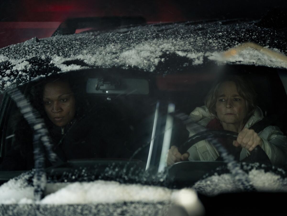 Two women in a car driving in the snow.