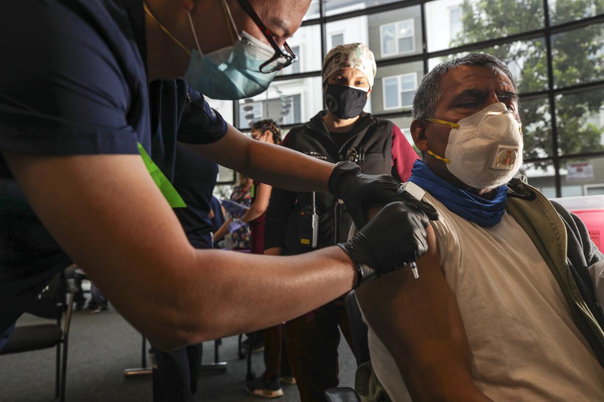 A person watches as a healthcare worker administers a vaccine.