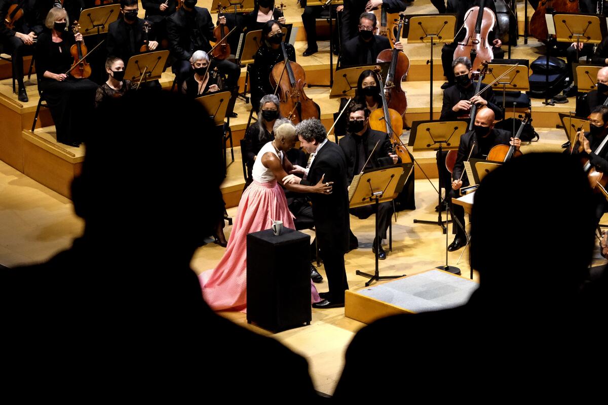 Cynthia Erivo and Gustavo Dudamel are seen through a crowd, embracing on stage.