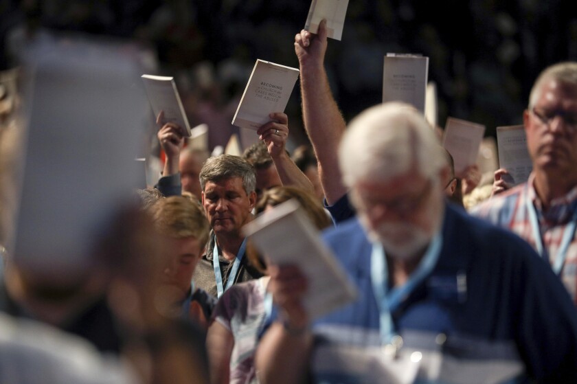 FILE - In this Wednesday, June 12, 2019 file photo, Bill Golden, and thousands of others, hold up copies of a training handbook related to sexual abuse within Southern Baptist churches during a speech by SBC President J. D. Greear on the second day of the SBC's annual meeting in Birmingham, Ala. As Southern Baptists prepare for their biggest annual meeting in more than a quarter-century in June 2021, accusations that leaders have shielded churches from claims of sexual abuse and simmering tensions around race threaten to once again mire the nation’s largest Protestant denomination in a conflict that can look more political than theological. ( Jon Shapley/Houston Chronicle via AP, File)