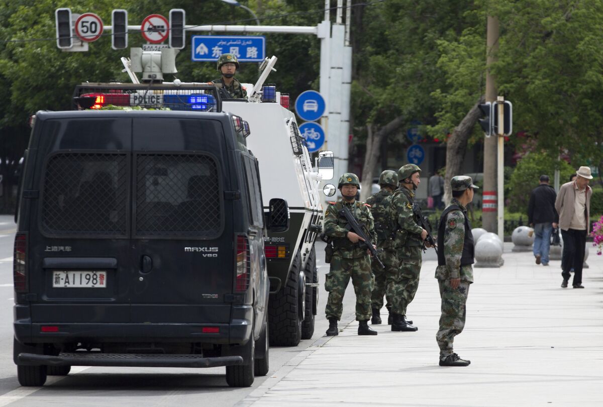 Chinese police stand guard next to their armored personnel carrier parked near the People's Square in Urumqi.