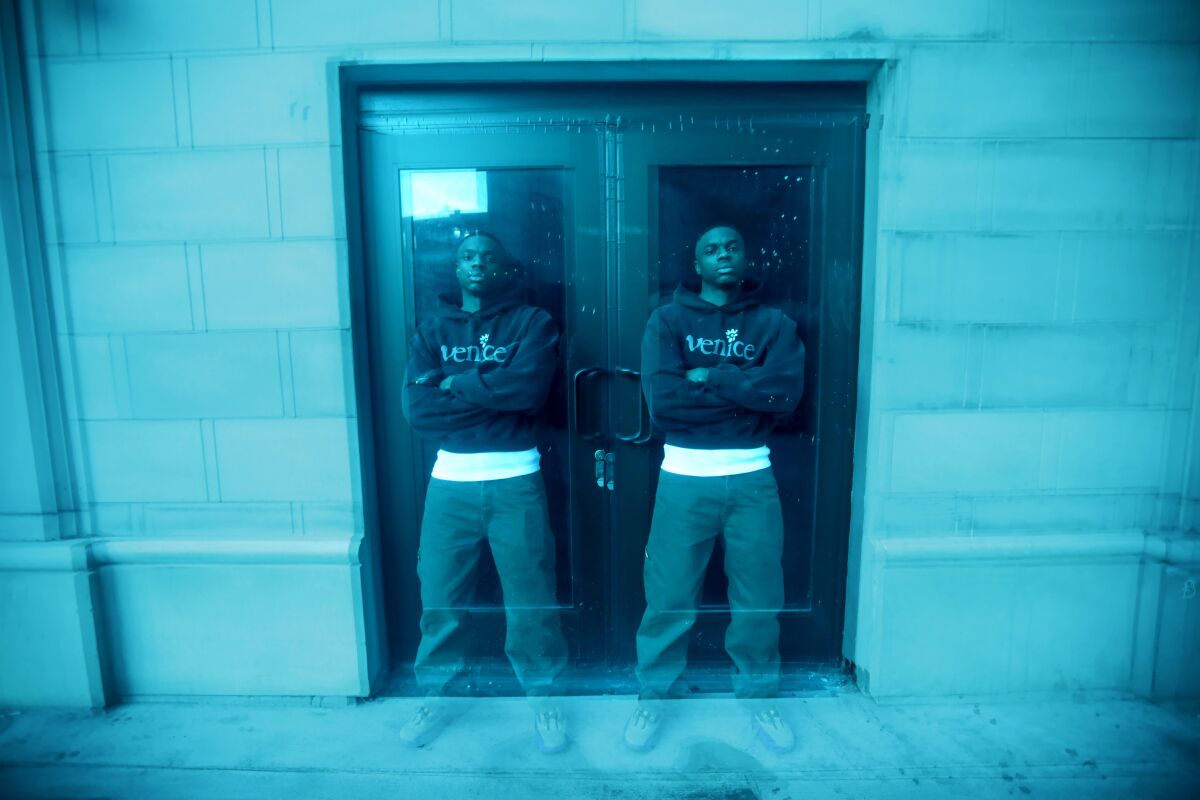 A man is seen leaning against a door twice using a camera effect.
