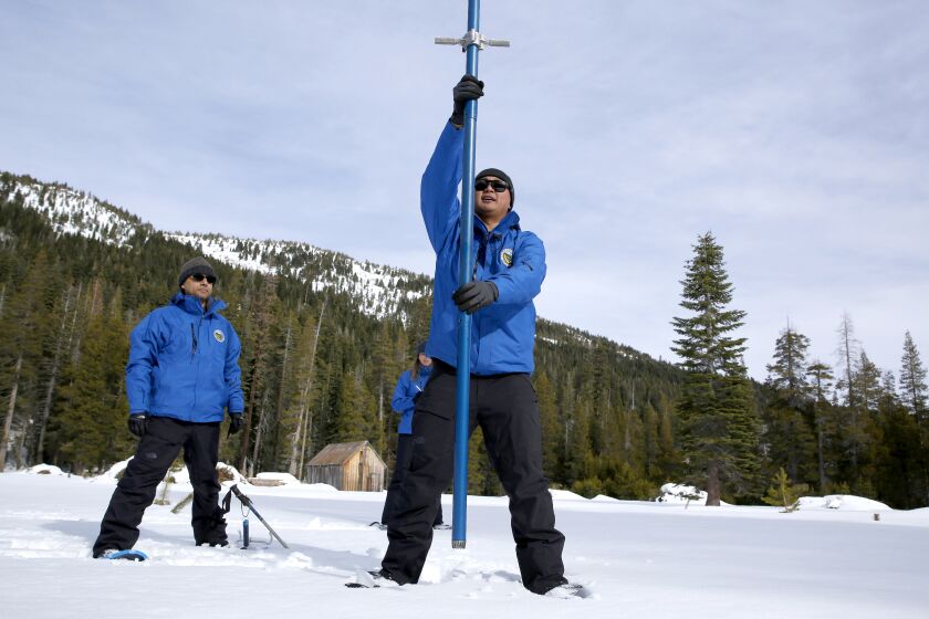 Sean de Guzman, right, chief of snow surveys for the California Department of Water Resources, plunges a snow survey tube into the snowpack during the first snow survey of the season at Phillips Station near Echo Summit, Calif., Thursday, Jan. 2, 2020. The survey found the snowpack at 33.5 inches deep with a water content of 11 inches which is 97% of average at this location at this time of year. Also seen are DWR's Ramesh Gautam, left, and Lauren Miller, behind de Guzman. (AP Photo/Rich Pedroncelli)