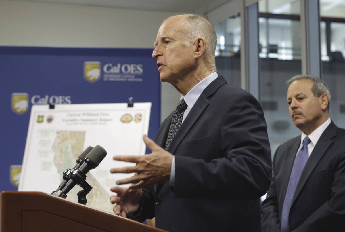 Gov. Jerry Brown, shown here discussing wildfires on Monday, has been criticizing Republican presidential candidates for neglecting to discuss climate change.