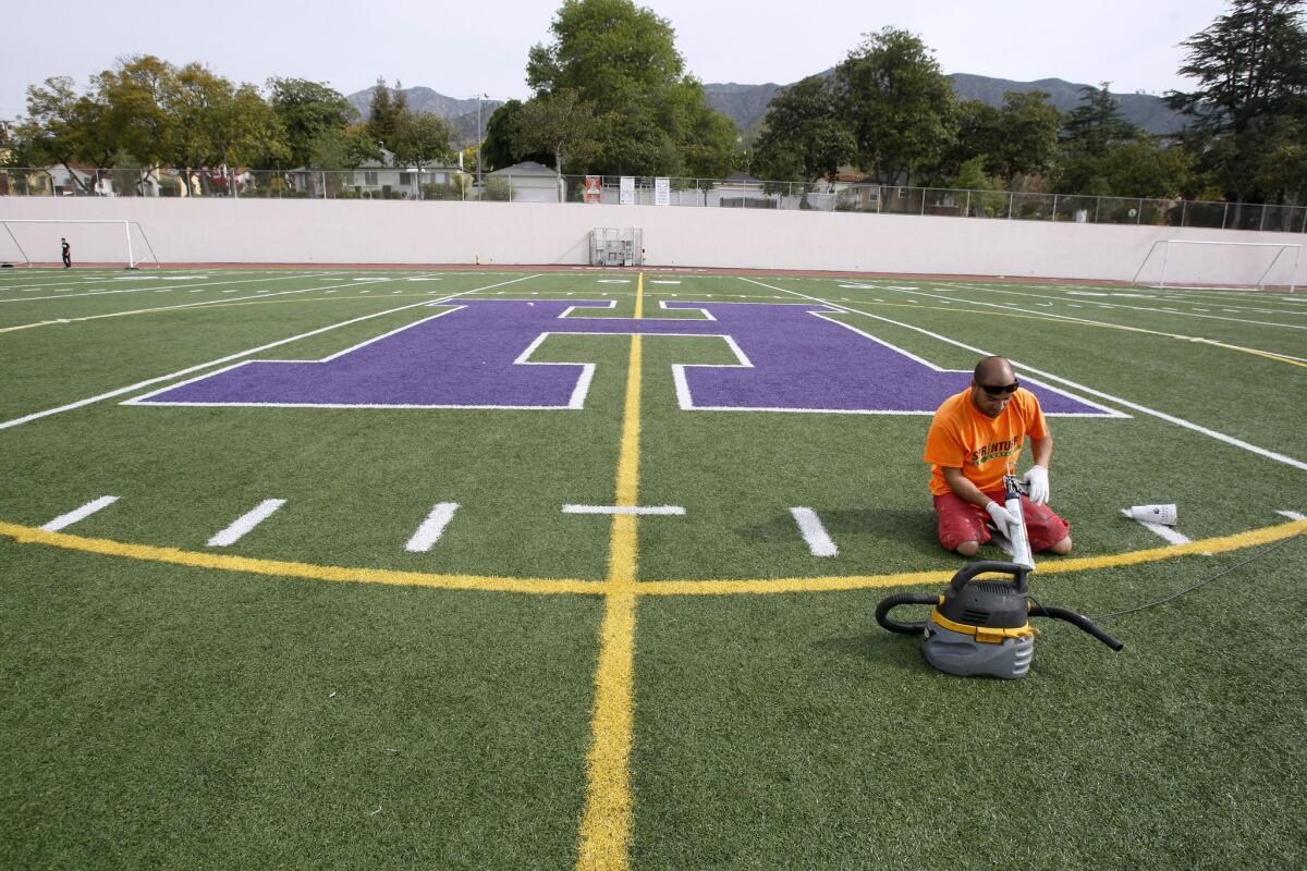 Talon Elkins from Sprinturf puts the finishing touches on the new Hoover High School field at the Glendale school on Friday, April 4, 2014. The field was recently renovated and dedicated.