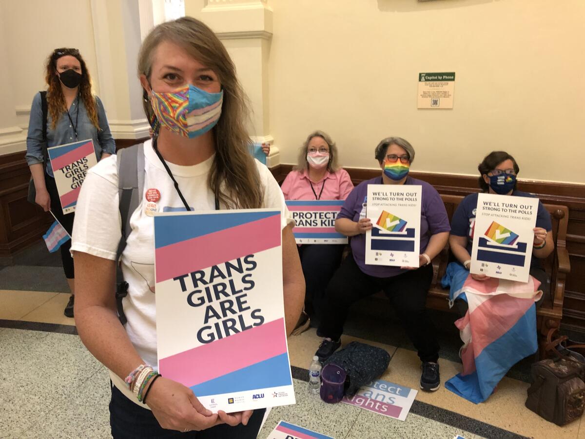 A protester holds a sign that says "Trans Girls Are Girls."