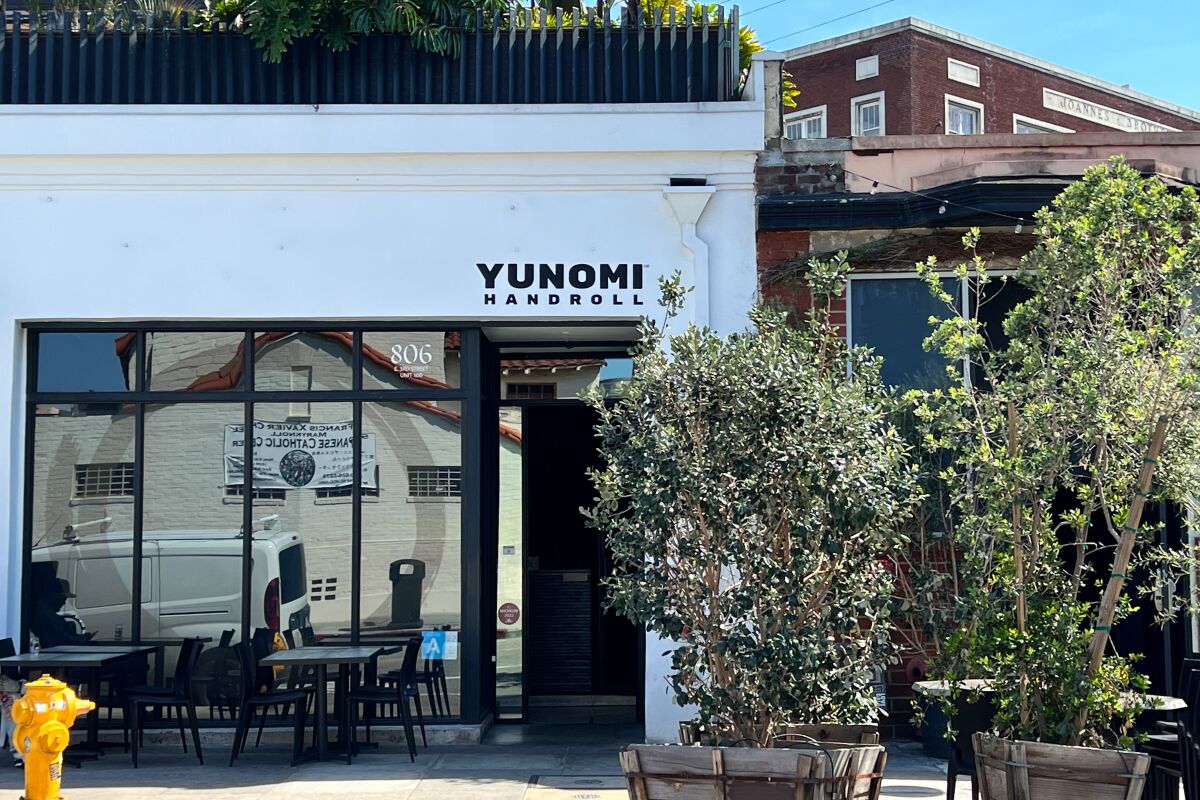 A white building with the word Yunomi over the door, with glass storefront