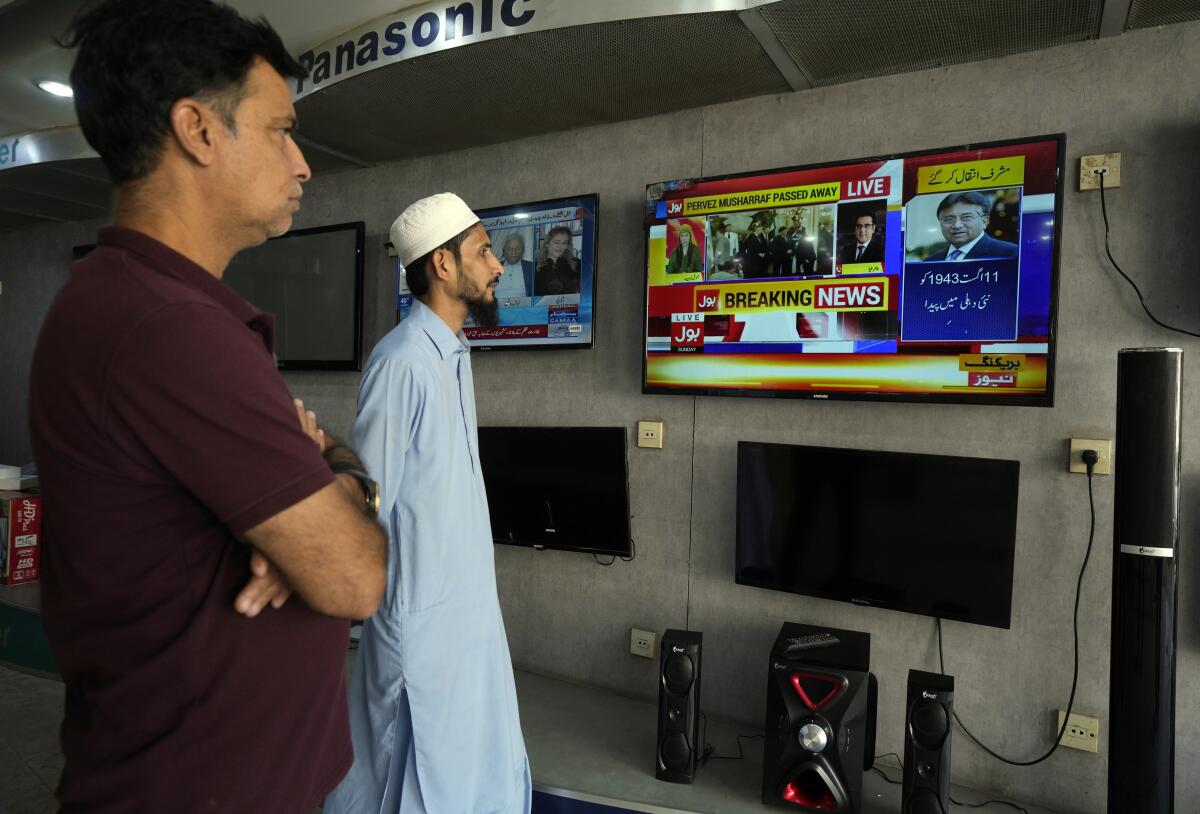 Pakistanis at a TV shop in Karachi watch coverage about the death of former President Musharraf.