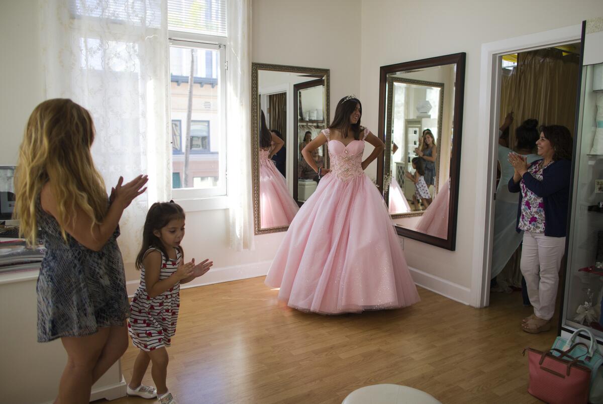 Natalie Anaya, 14, of Santa Ana gets cheers from her mom Ana Perez, sister Isabella Perez, 5, and shop owner Lilia Cerpas, right, while trying on a pink quinceañera dress at Genesis Bridal Boutique in Santa Ana.