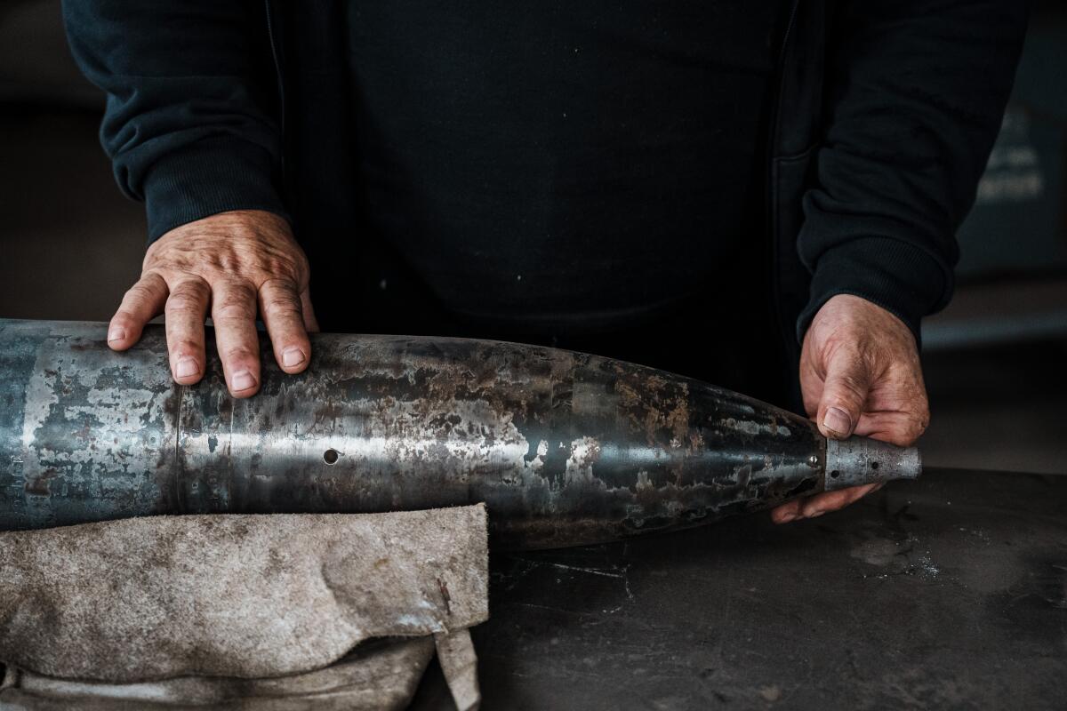 Artist Mikhail Reva examines a spent munition case. His sculptures are made from equal parts metal and rage.