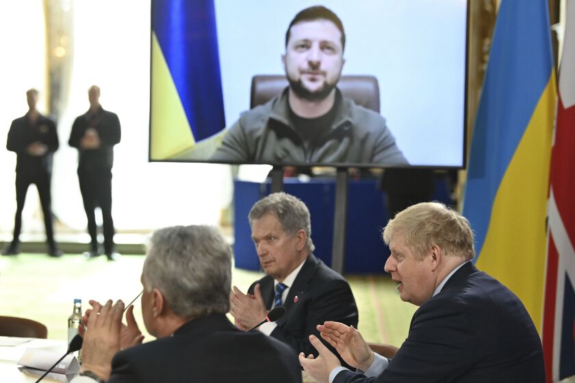British Prime Minister Boris Johnson and attendees applaud after Ukraine's President Volodymyr Zelensky addressed them by video link during a meeting of the the Joint Expeditionary Force (JEF), a coalition of 10 states focused on security in northern Europe, in London, Tuesday, March 15, 2022. (Justin Tallis/Pool Photo via AP)