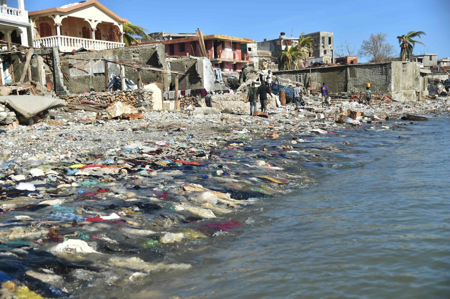 Haitians walk the site of destroyed houses and debris left by Hurricane Matthew in Haiti on Oct. 8, 2016.