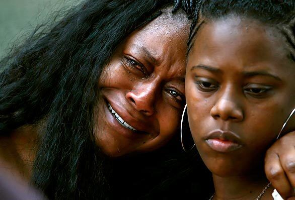 Cartasia Perkins, left, weeps with her sister Nichole Thompson along Flower Street.