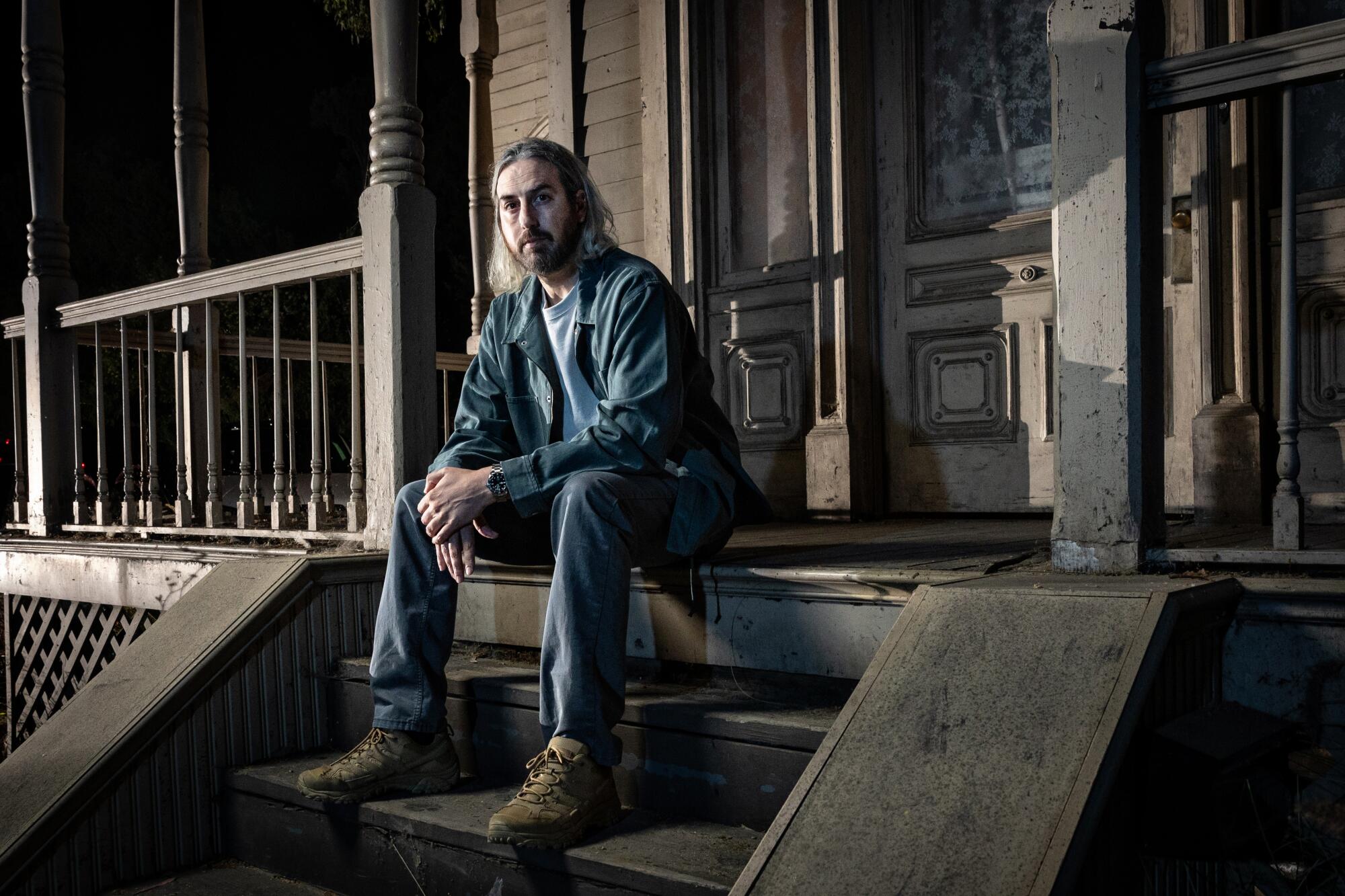 Unafraid, a man sits on the front steps of an iconic movie murder house.
