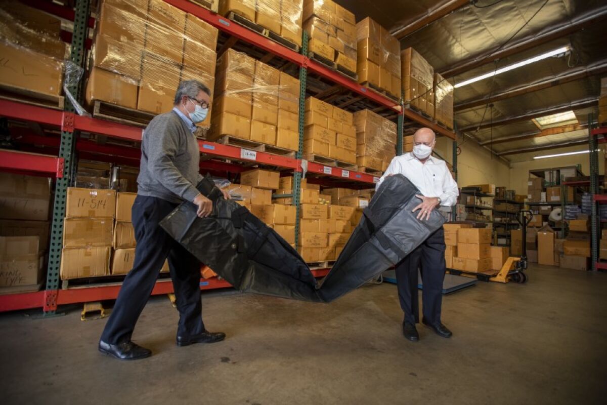 David Cameron and Abdul Salam of Salam International unpack a body bag at the company’s Laguna Hills warehouse.