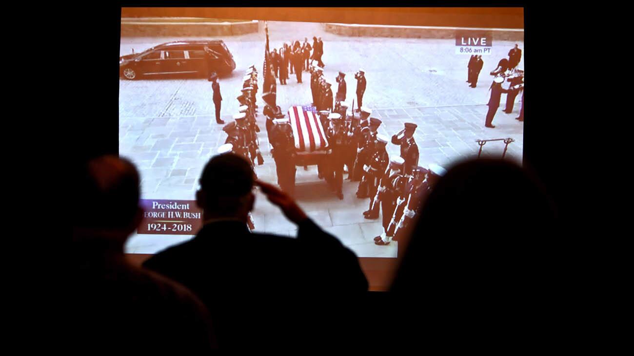 A visitor salutes as he watches the broadcast of the state funeral for President George H.W. Bush at the Richard Nixon Presidential Library and Museum, in Yorba Linda on Wednesday.