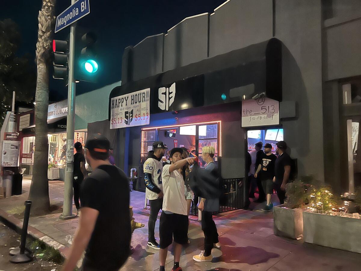 A few people on the street outside a bar.