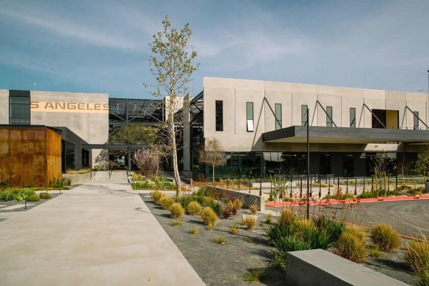 A low building, surrounded by new planting, reveals part of an old sign 