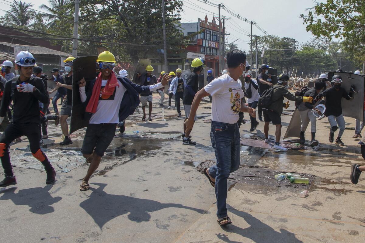 Anti-coup protesters retreat from the frontlines after riot policemen fire sound-bombs and rubber bullets in Yangon, Myanmar, Thursday, March 11, 2021. (AP Photo)