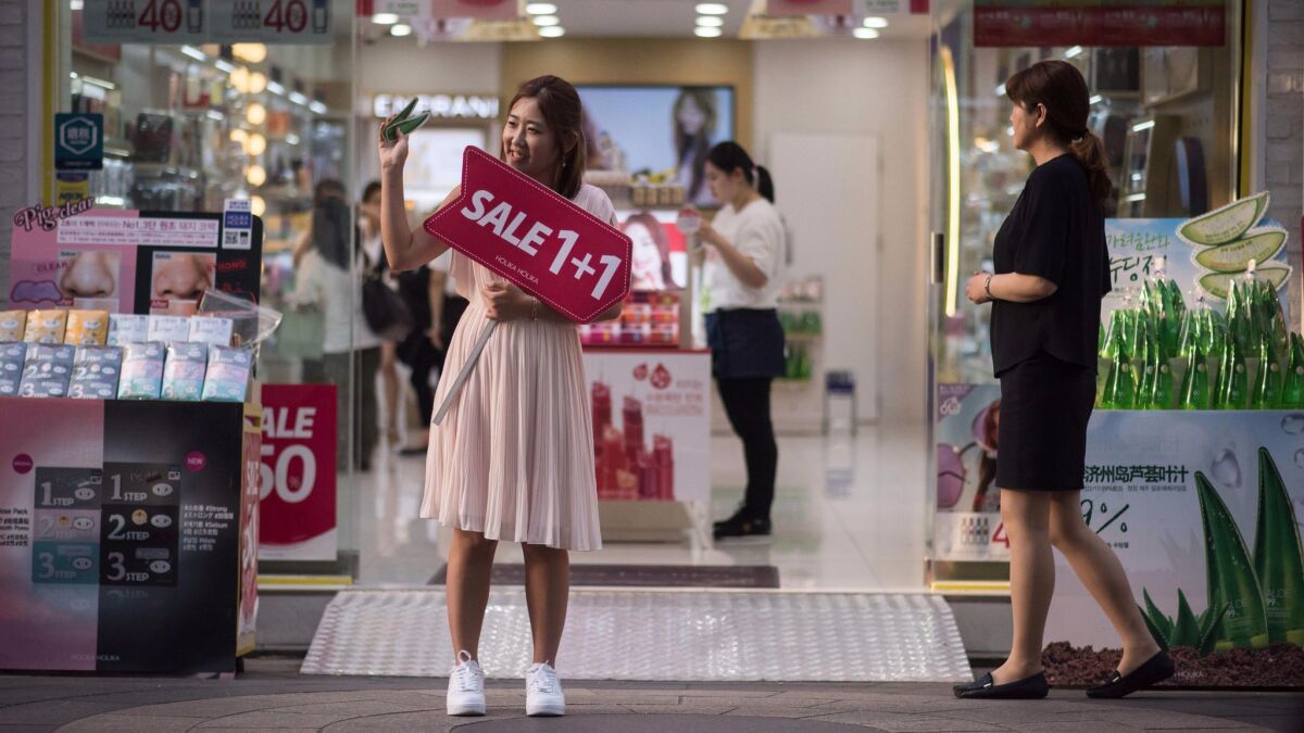 A salesperson advertises a sale in front of a cosmetics store in the popular Myeongdong shopping area of Seoul.