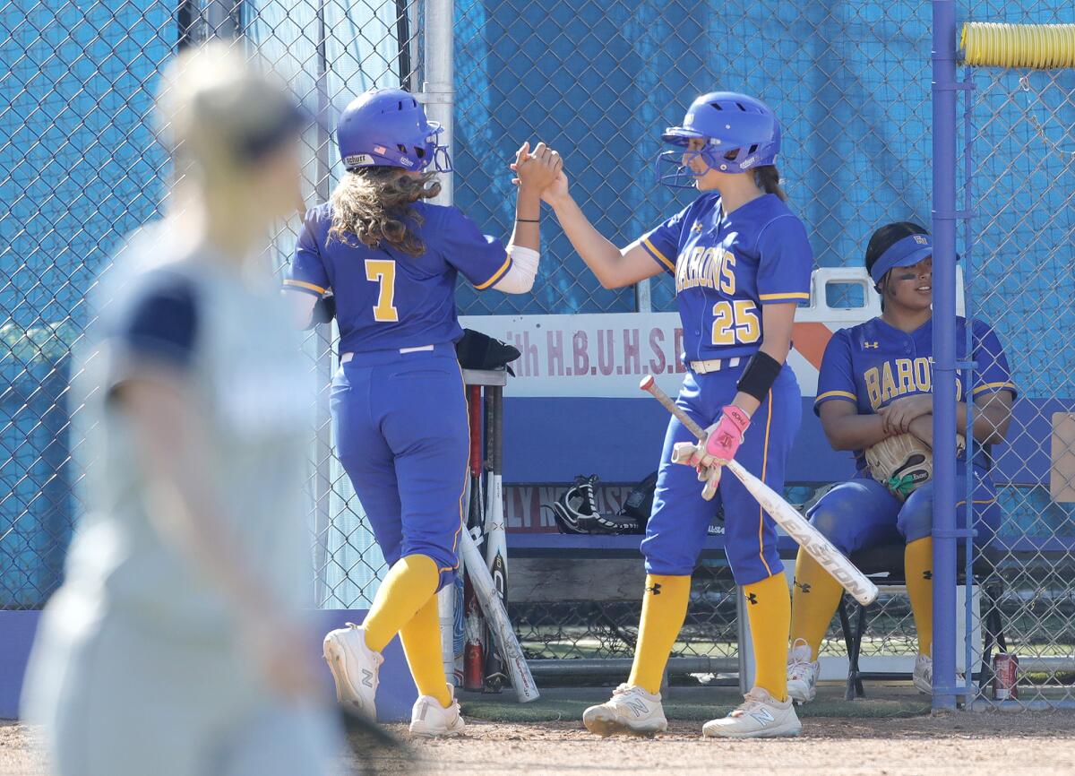 Fountain Valley's Marissa Sardinas (7) high fives Samantha Estrada (25) after scoring a run against Newport Harbor.