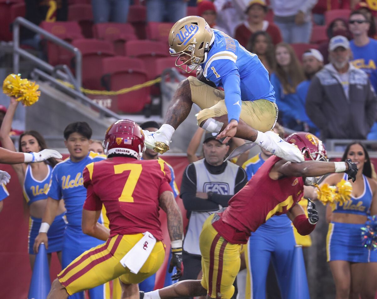 UCLA quarterback Dorian Thompson-Robinson hurdles USC safety Chase Williams in front of cornerback Isaac Taylor-Stuart.