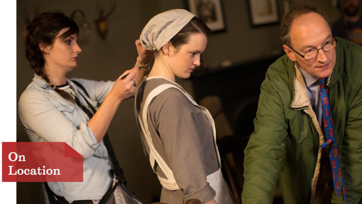 Makeup and hair artist Amy Boyd, left, works with Sophie McShera, who plays Daisy, as Alastair Bruce, the historical advisor for "Downton Abbey" goes over a scene for the final season.