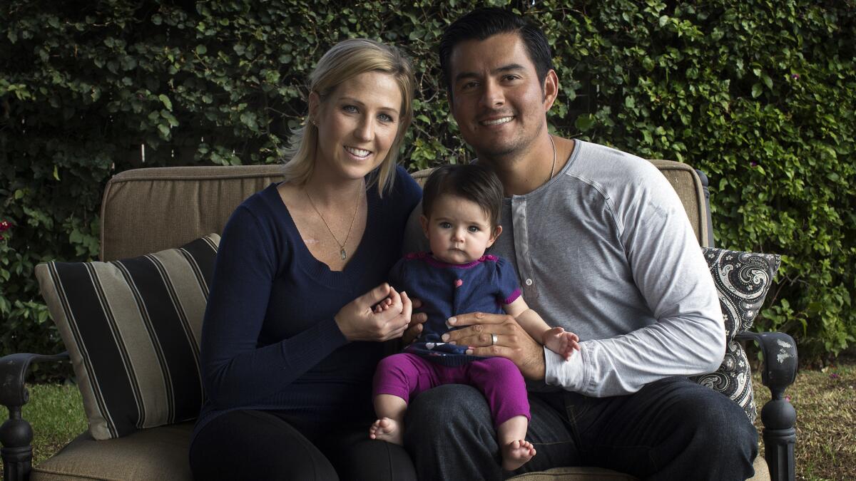 Recently acquired Angels pitcher Cesar Ramos, right, sits at home with his wife, Melanie, and their four-month-old daughter, Addison, on Nov. 19. Melanie was diagnosed with Hodgkin's lymphoma more than two years ago and underwent nine months of chemotherapy.