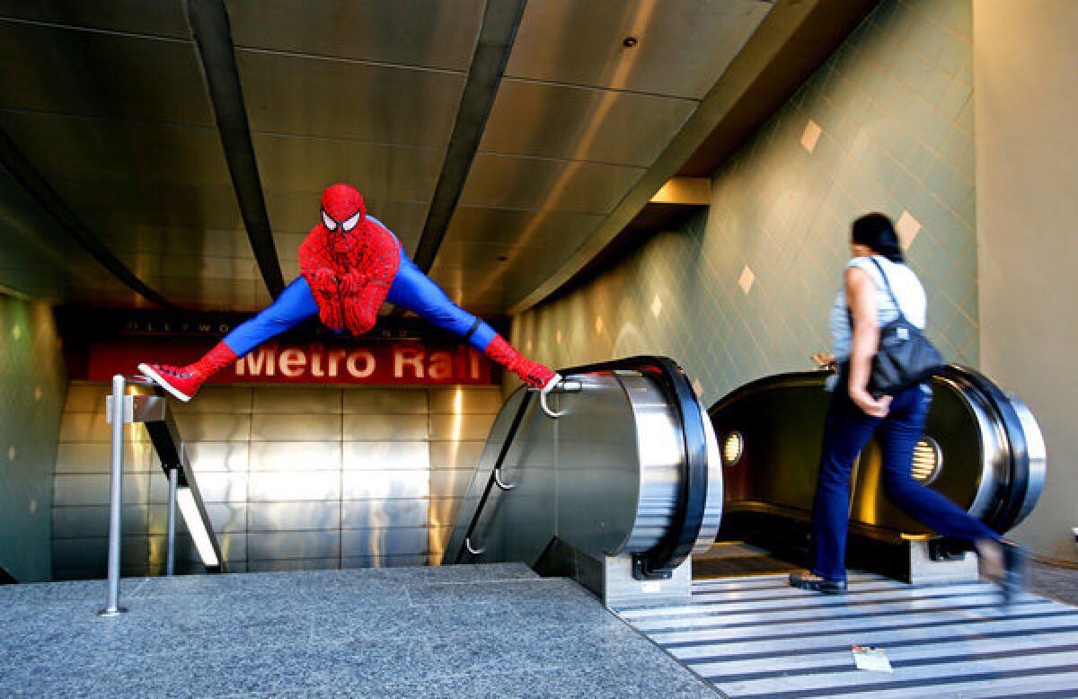 Christopher Loomis, dressed up as Spider-Man, performs near the Metro Red Line entrance on Hollywood Boulevard near Highland Avenue.