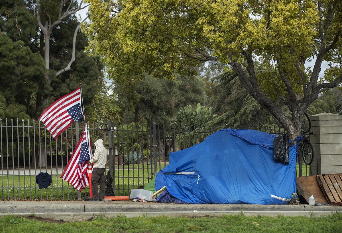 A man tends to a flag at a homeless encampment just outside the West L.A. VA campus in 2020. 