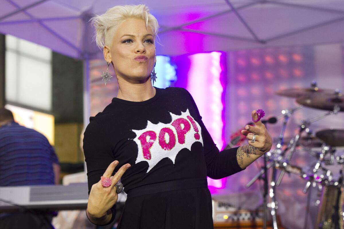 Pink wears a black top with the word Pop! printed on the front in pink while she makes peace signs with her fingers.