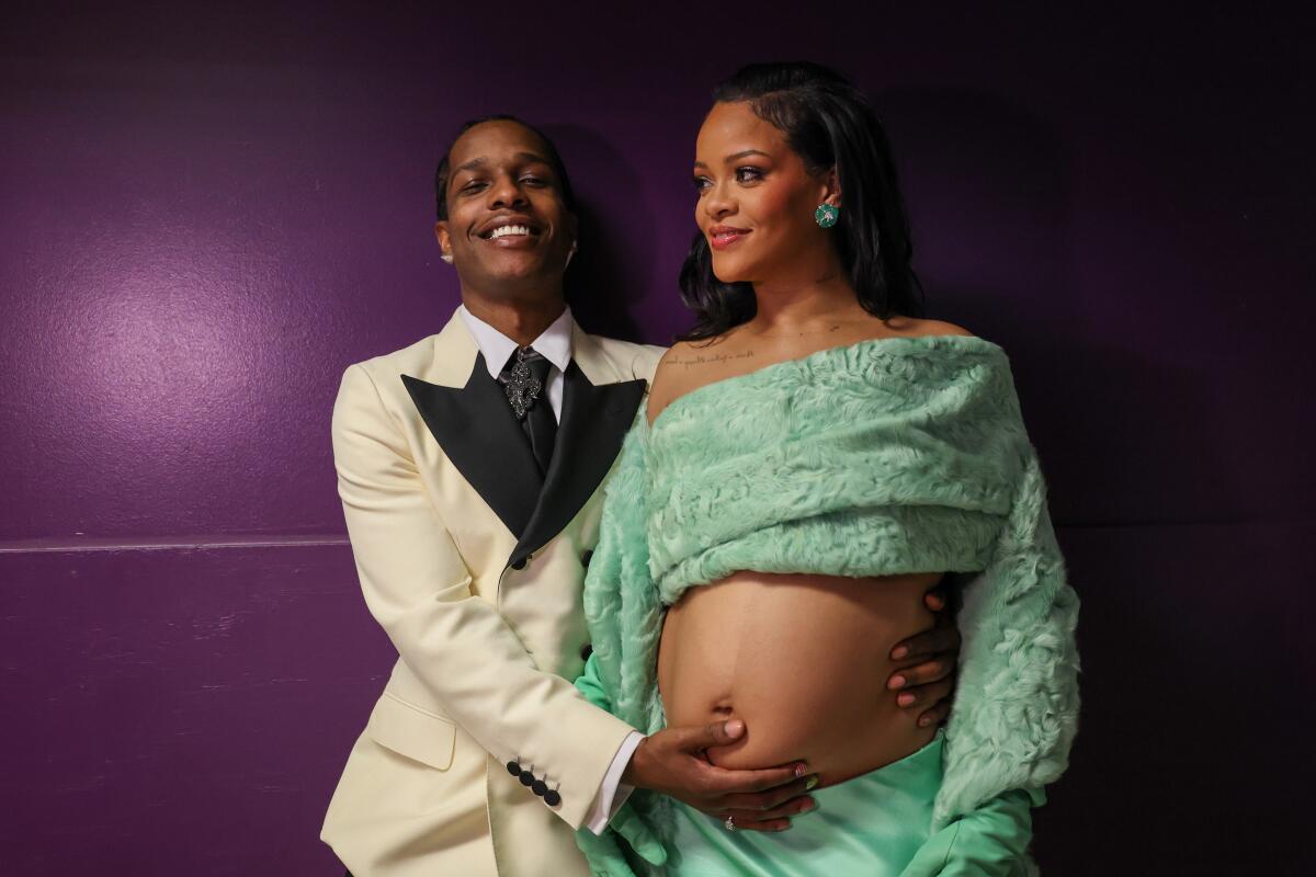 ASAP Rocky holds the bare, pregnant belly of Rihanna with both hands as she looks off to the side