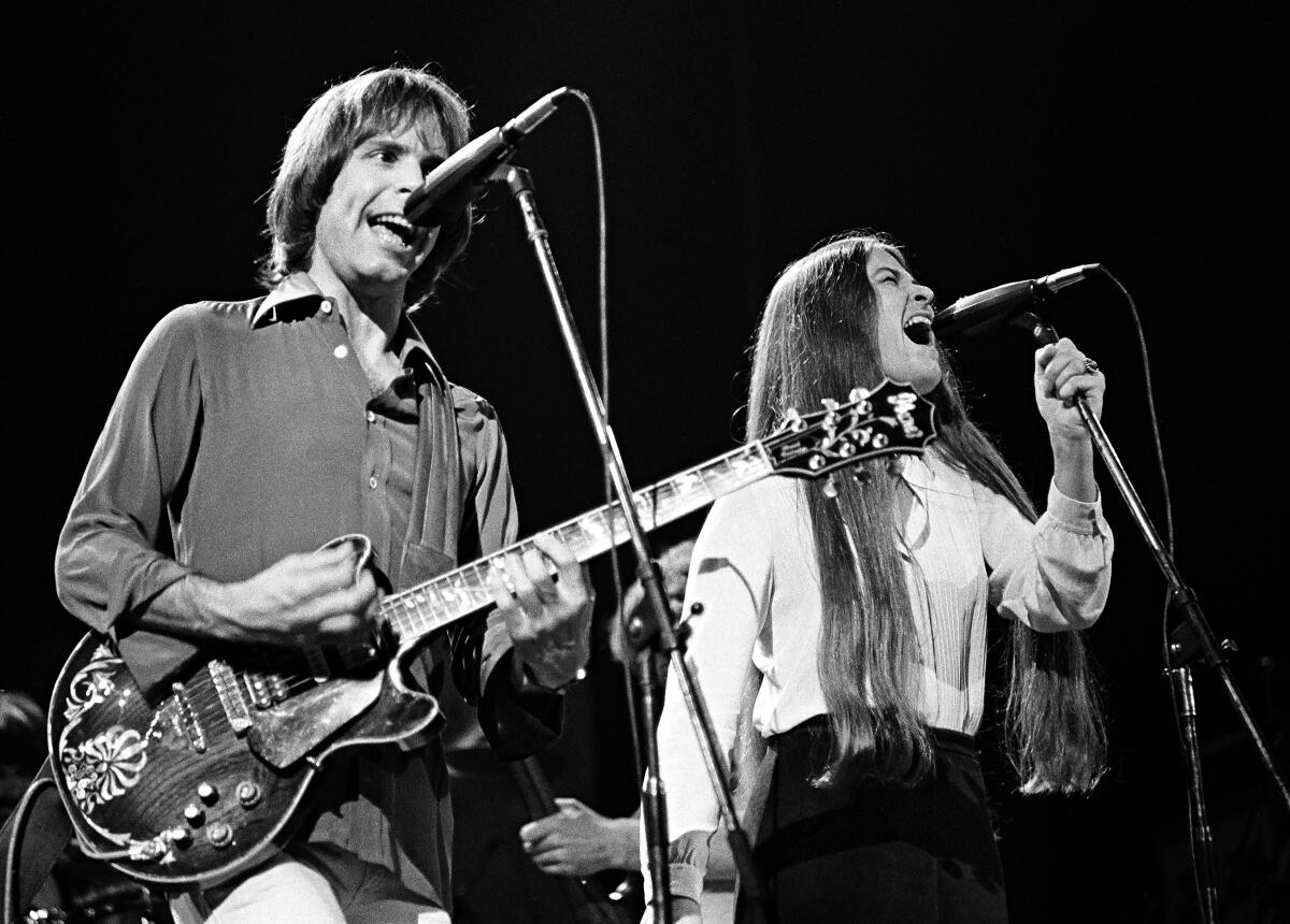 A man with an electric guitar and a female singer performing