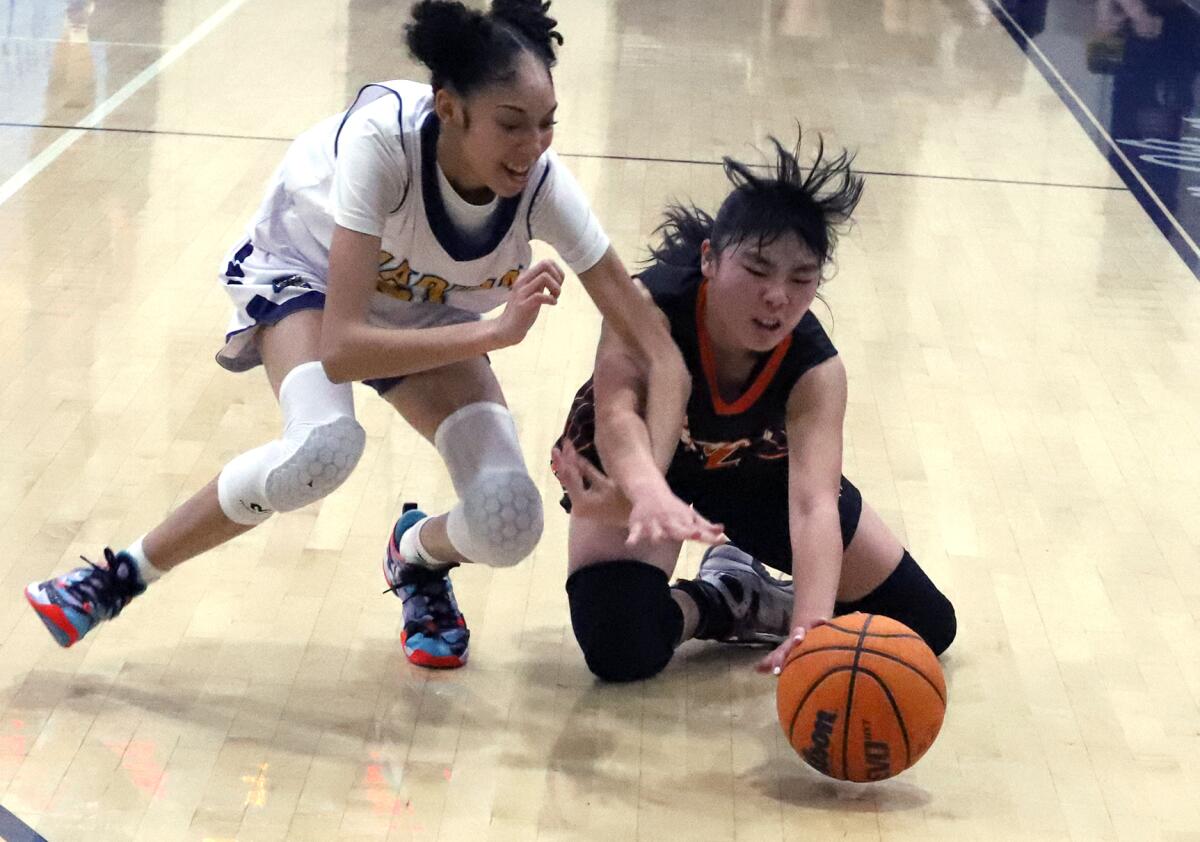 Marina's Anaya Rivera (21) and Huntington Beach's Lauren Matsumoto (12) dive for the loose ball in a Wave League game.