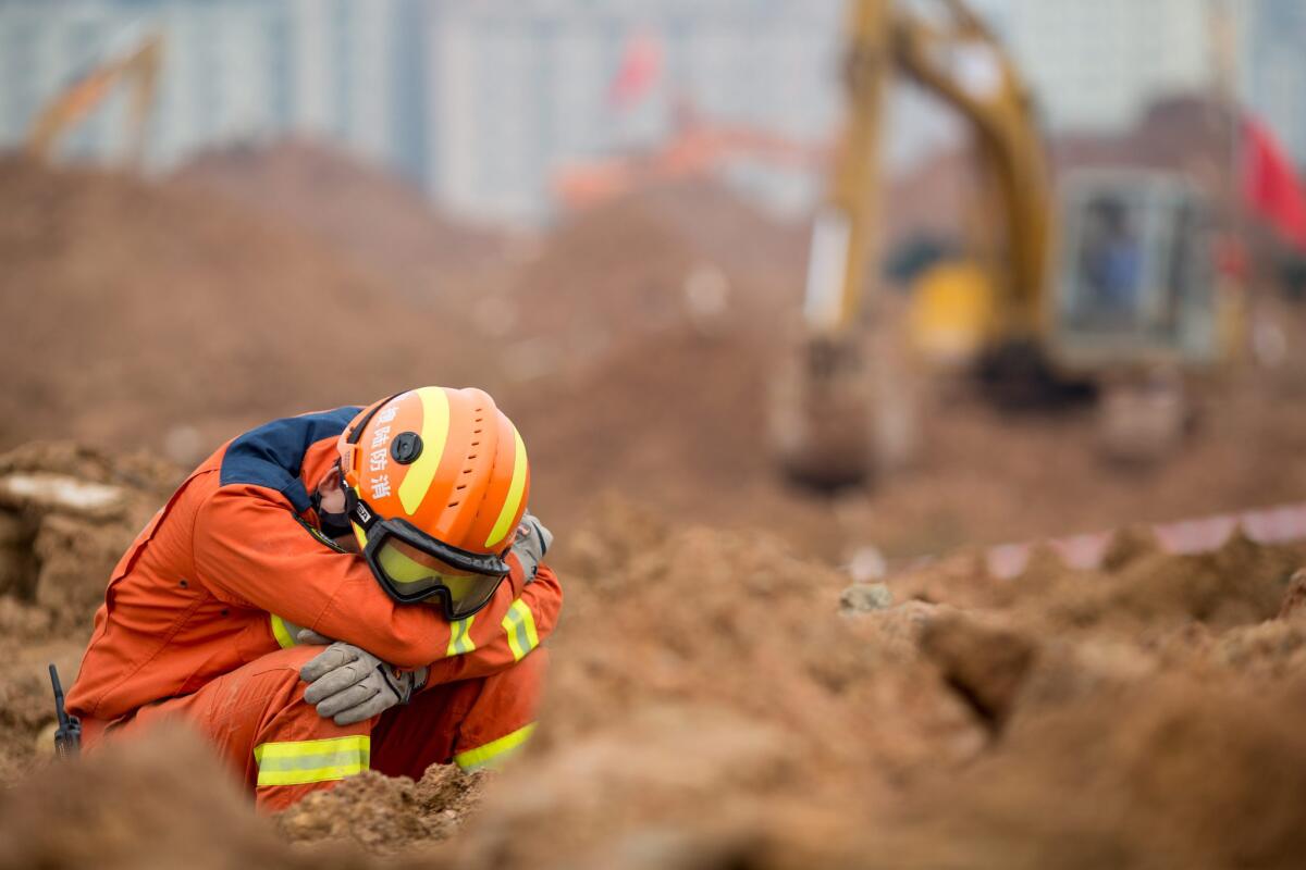 An exhausted rescuer takes a rest as he sits amid mud and rubble after a landslide in Shenzhen in south China's Guangdong province. More than 91 people were reported missing.