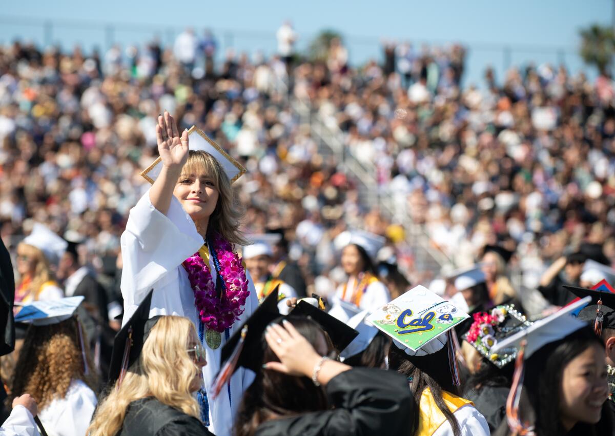A graduating senior waves to loved ones in the stands at Huntington Beach High on Wednesday.