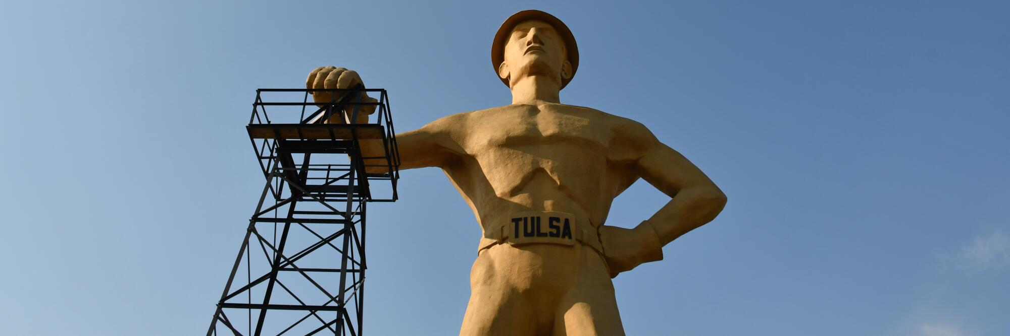 Statue of "Golden Driller," Tulsa, showing a muscular oil worker with one hand on an oil derrick.