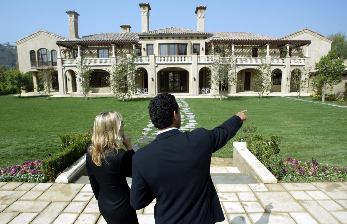 Two Realtors point at a mansion.