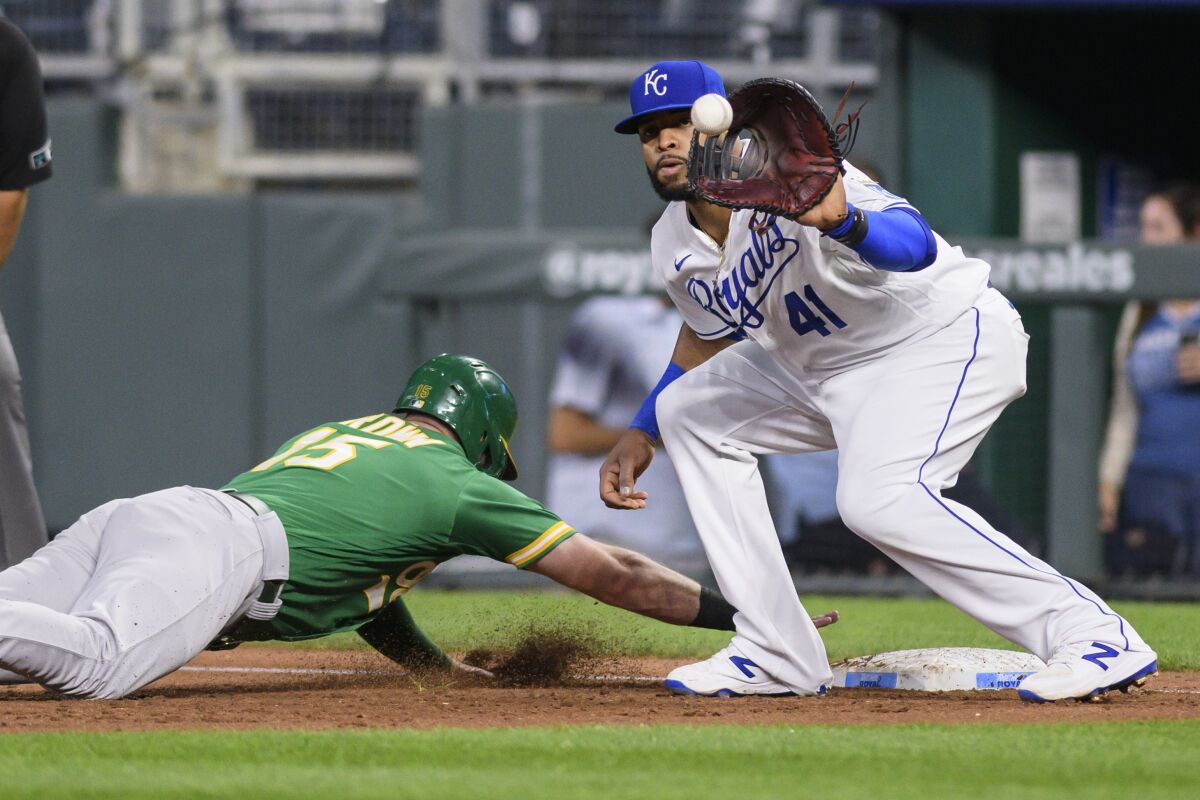The Oakland Athletics' Seth Brown dives back ahead of the throw to Kansas City Royals first baseman Carlos Santana during the second inning of a baseball game, Tuesday, Sept. 14, 2021 in Kansas City, Mo. (AP Photo/Reed Hoffmann)